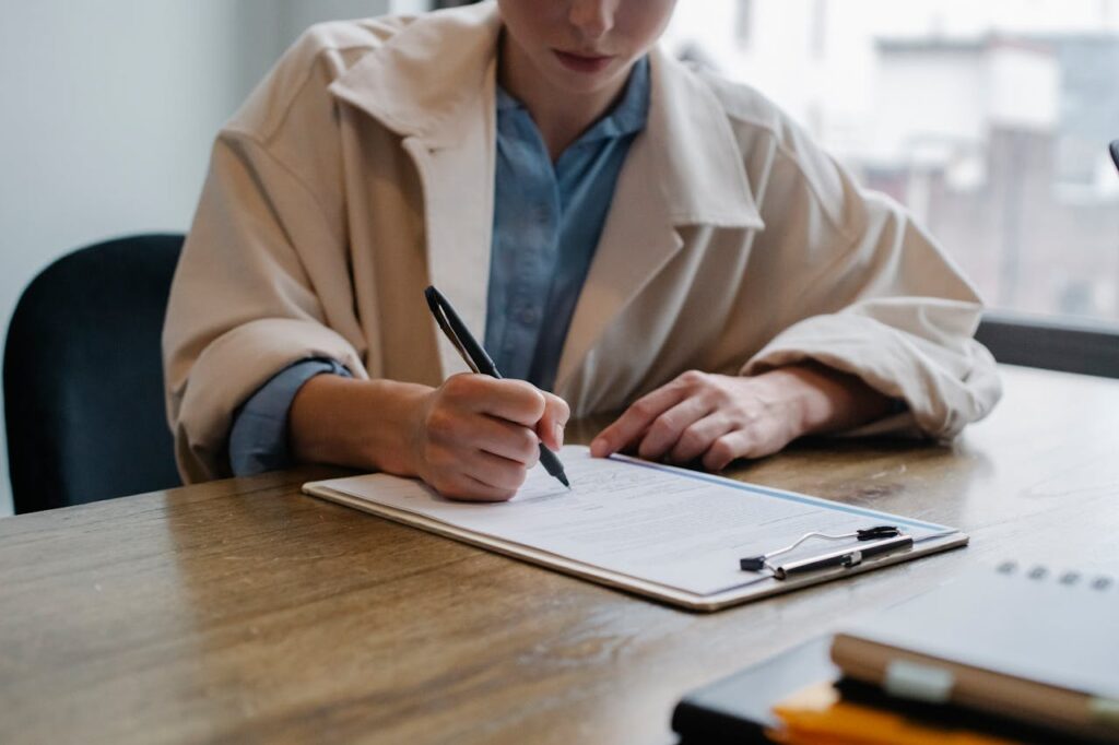 Focused woman writing in clipboard while hiring candidate